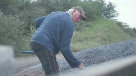 man throwing sand into pickup bed rack focus