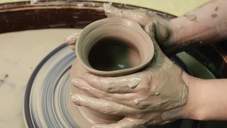 las manos de la mujer en la rueda de la cerámica. el artesano el artista da forma a la olla