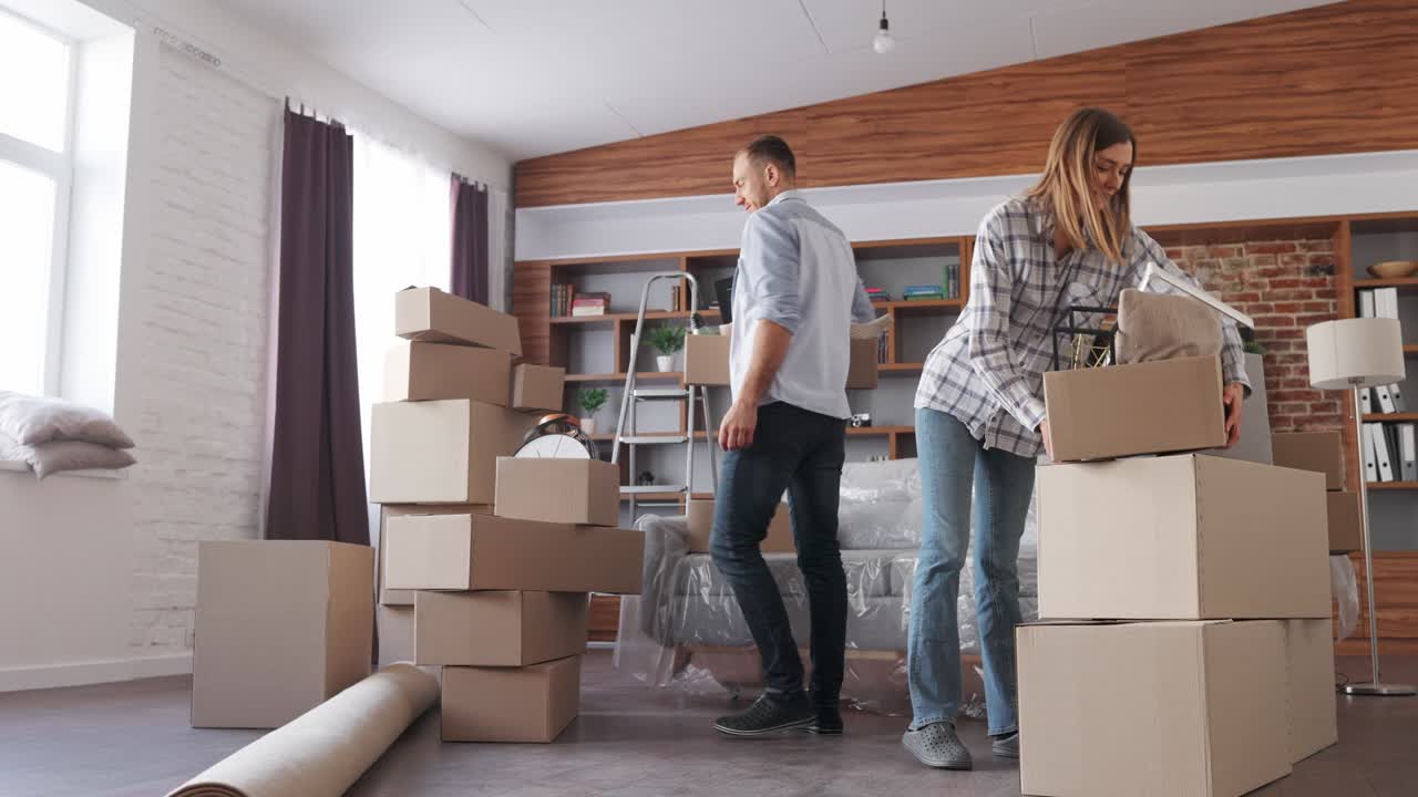pareja joven llevando cajas en un nuevo apartamento el día de la mudanza. nuevo alojamiento o apartamento alquilado. retrato de propietarios felices el día del traslado. bienes raíces y concepto de alquiler. préstamo hipotecario para familia joven