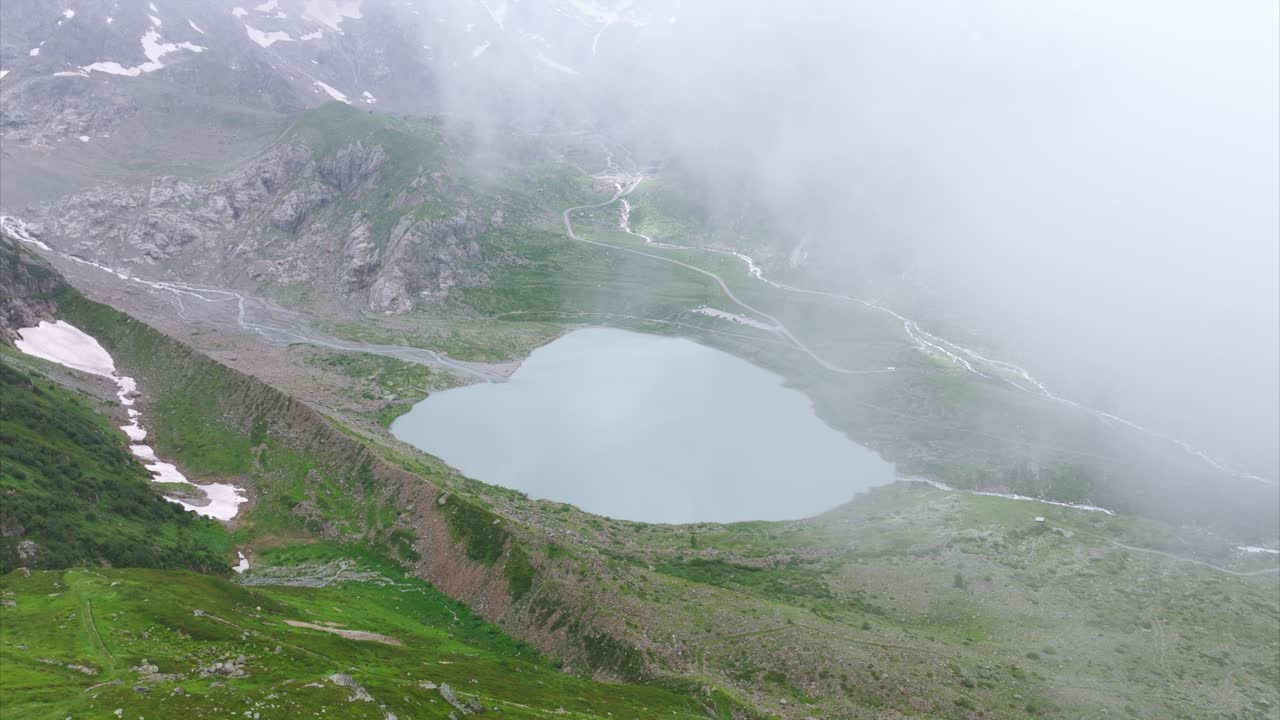 воздушный вид спокойного горного озера, окруженного пышной зеленью и неровной местностью в швейцарских альпах возле перевала сурен