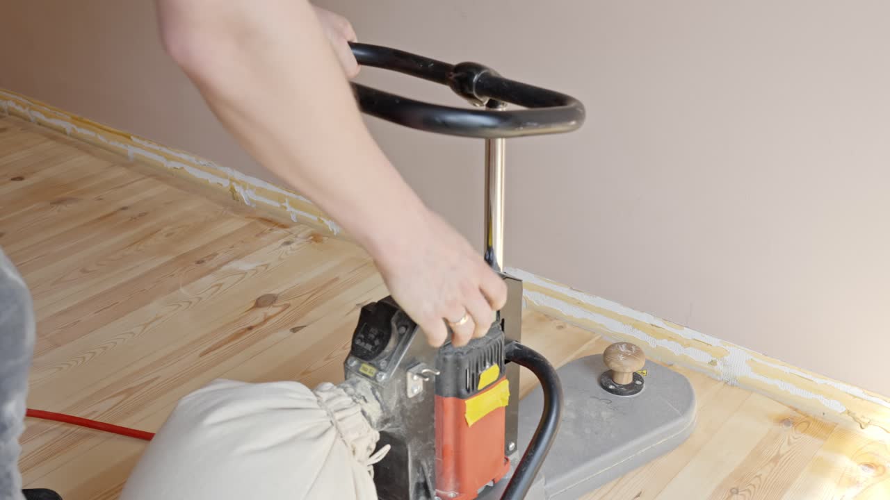 Preparing a solid wood floor for varnishing by sanding the edges and corners