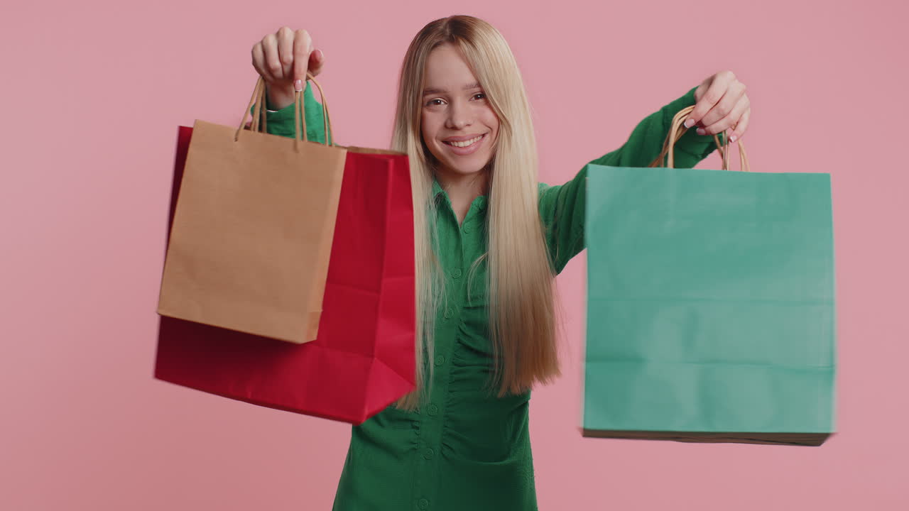 Shopaholic woman showing shopping bags advertising discounts smiling looking amazed with low prices