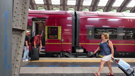 people boarding and walking past a train