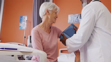 Médico-Varón-Afroamericano-Tomando-La-Presión-Arterial-De-Una-Paciente-Caucásica-Mayor-En-El-Hospital