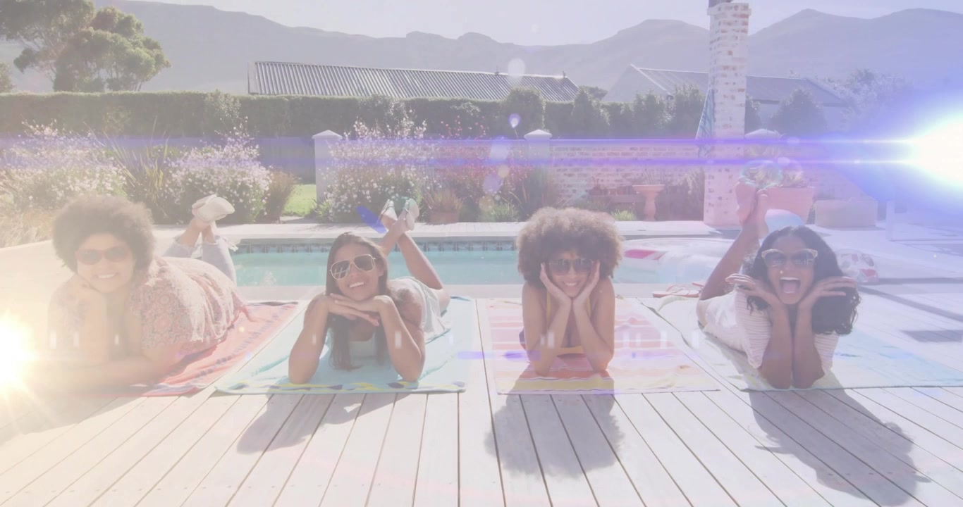 Friends lying on towels under animated flare lowering sunglasses for playful moment in lifestyle ad