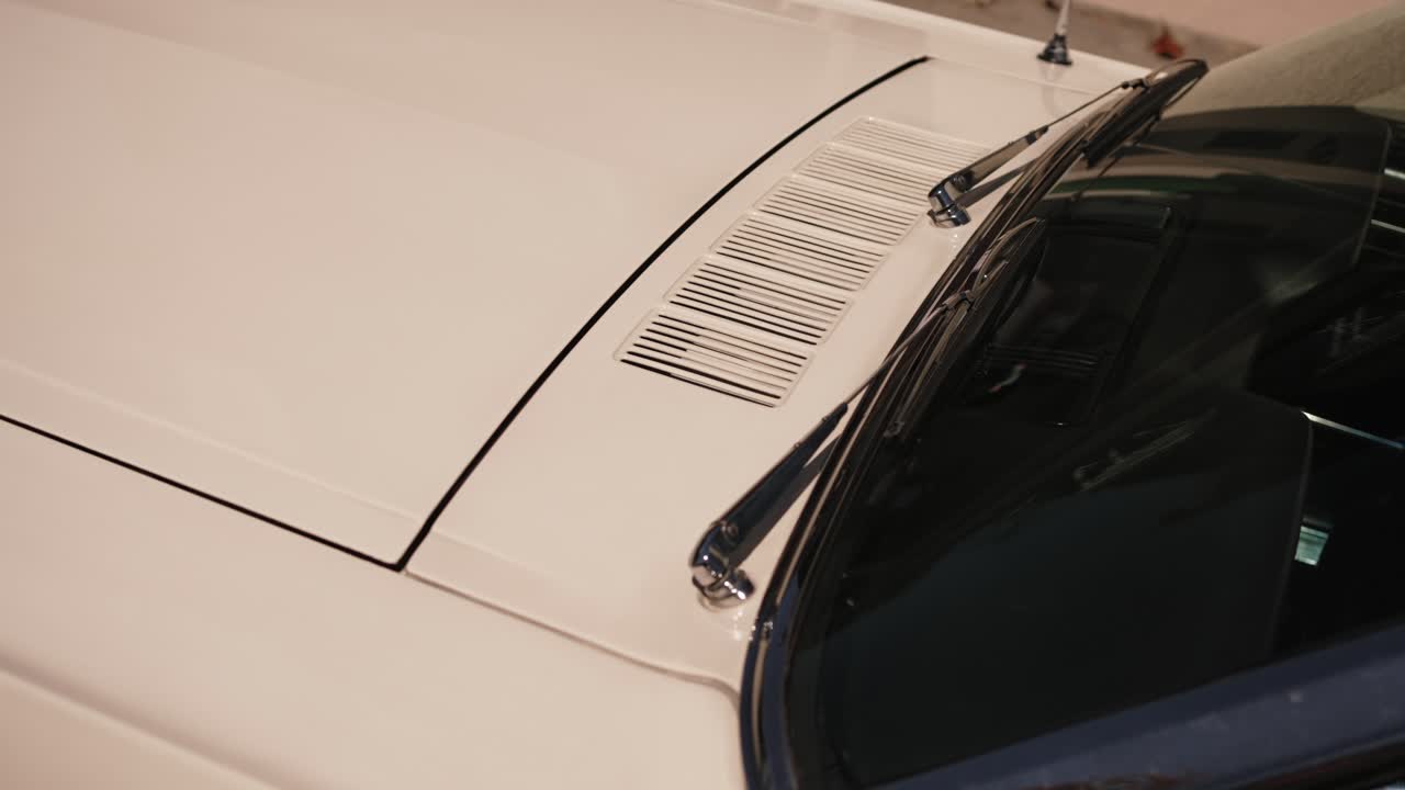 Detailed view of a vintage car hood with chrome windshield wipers and vents