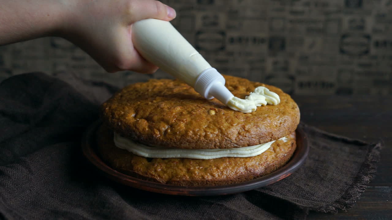 당근 케이크 장식. 셰프가 파이핑 봉투로 버터 크림을 부어