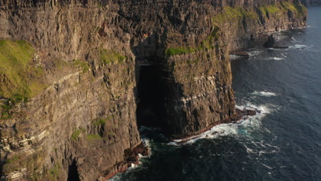 Bandada-De-Pájaros-Volando-Alrededor-De-La-Roca.-Altas-Paredes-Verticales-De-Acantilados-Sobre-El-Mar-Ondulado-Iluminado-Por-El-Sol-De-La-Hora-Dorada.-Acantilados-De-Moher,-Irlanda