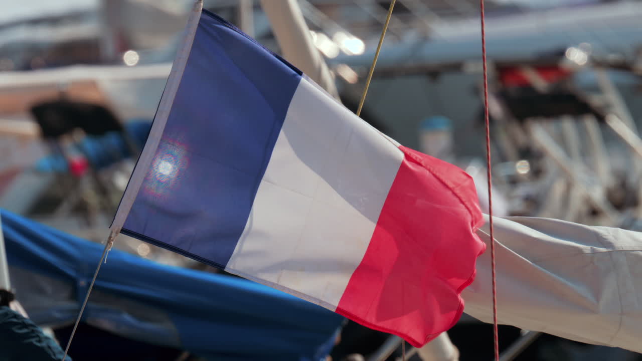 Close up of the French flag fluttering gently near boats in a marina