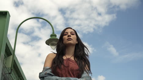 Low-angle-of-gorgeous-hispanic-brunette-while-modeling-and-walking-towards-the-camera,-with-a-floral-dress-and-denim-jacket