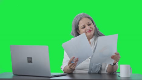 una mujer india alegre, gerente sénior, leyendo informes de negocios, pantalla verde
