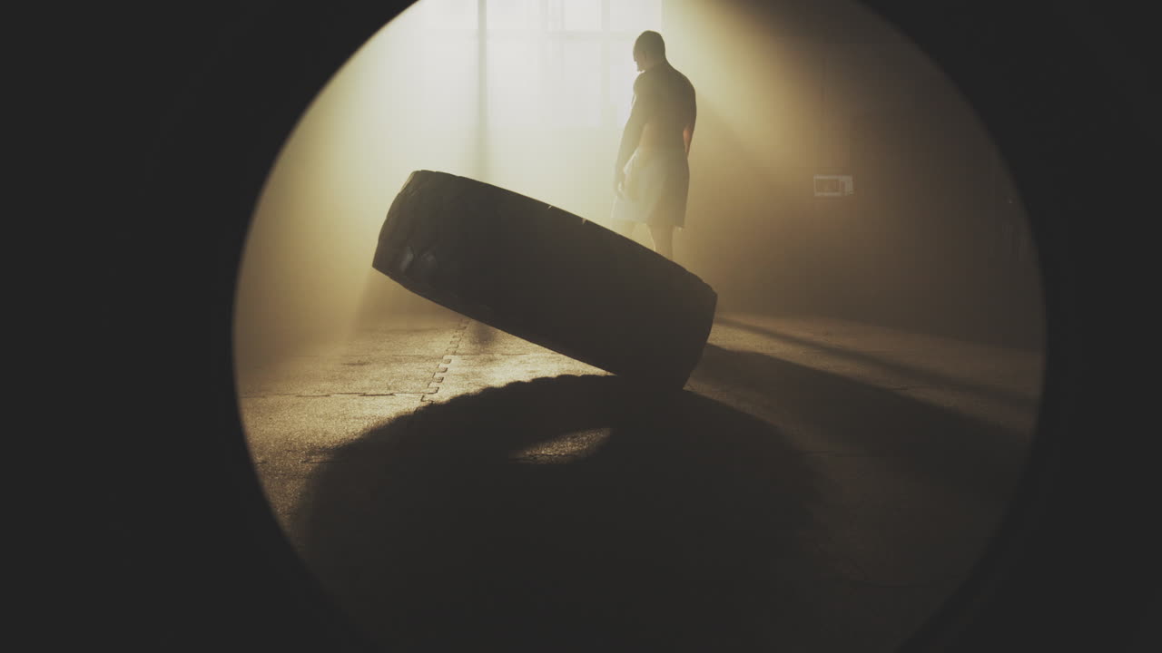 Man doing tire flip exercise in gym