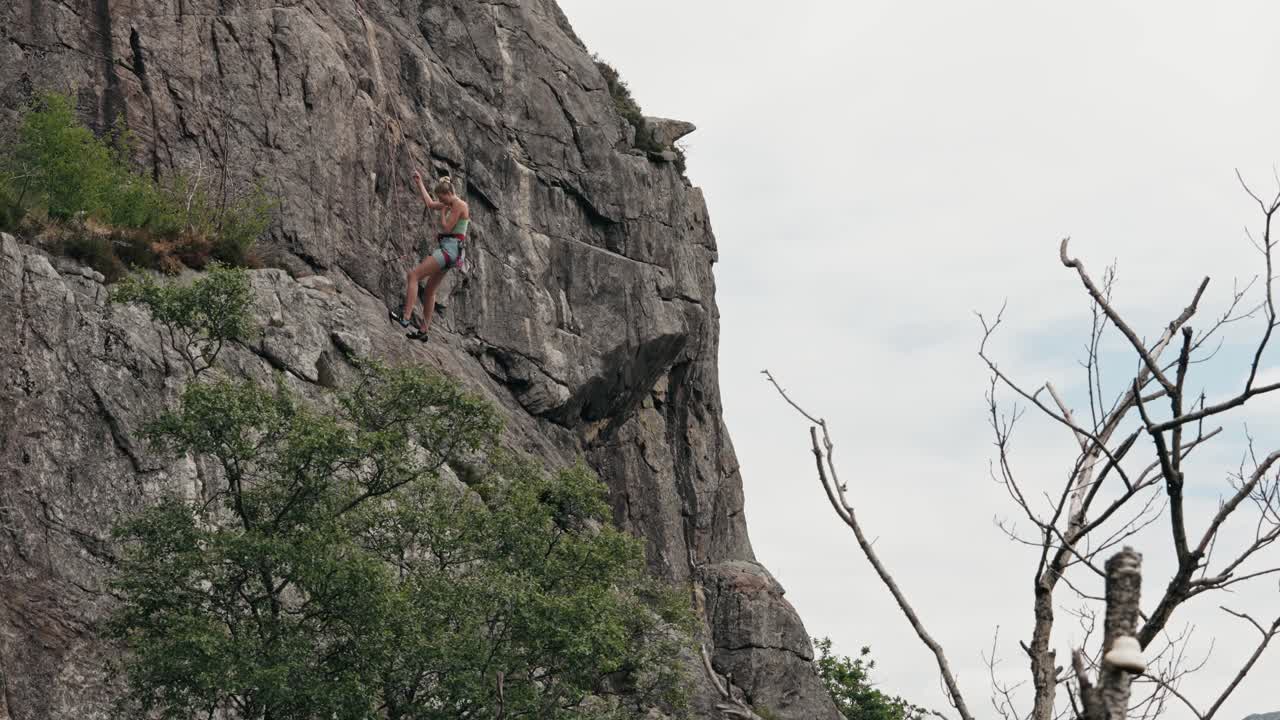 una mujer hermosa bajando por un acantilado rocoso, vista en cámara lenta