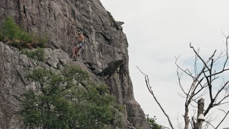 young beautiful woman climbing down rocky cliff, slow motion view