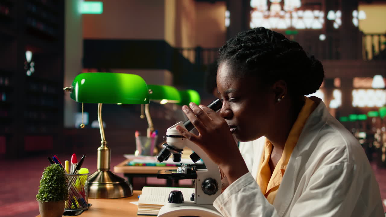 Female science student examines cells under microscope for scientific research