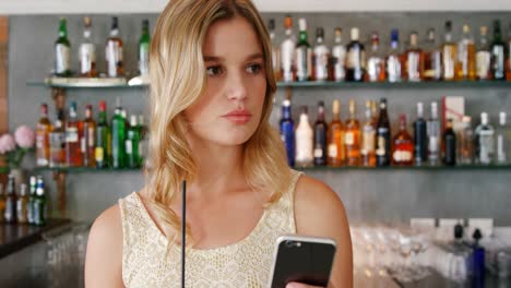 hermosa mujer usando teléfono móvil mientras toma un cóctel
