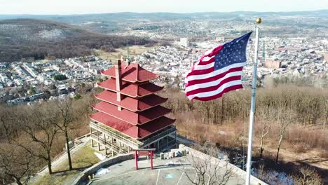 Antena-Sobre-La-Lectura-Del-Templo-Asiático-De-Pensilvania-Y-La-Bandera-Americana-Con-El-Fondo-De-La-Ciudad-1