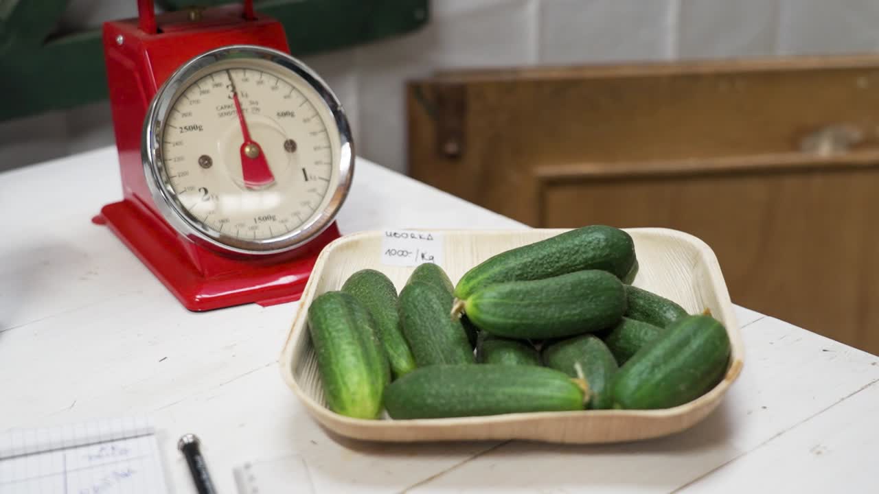 Fresh cucumbers in a tray next to a vintage red kitchen scale