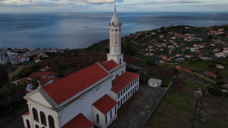 vista aérea de la iglesia de sao martinho en funchal, madeira: órbita desde la parte posterior de la hermosa iglesia durante la puesta de sol y con vistas a la ciudad y el océano