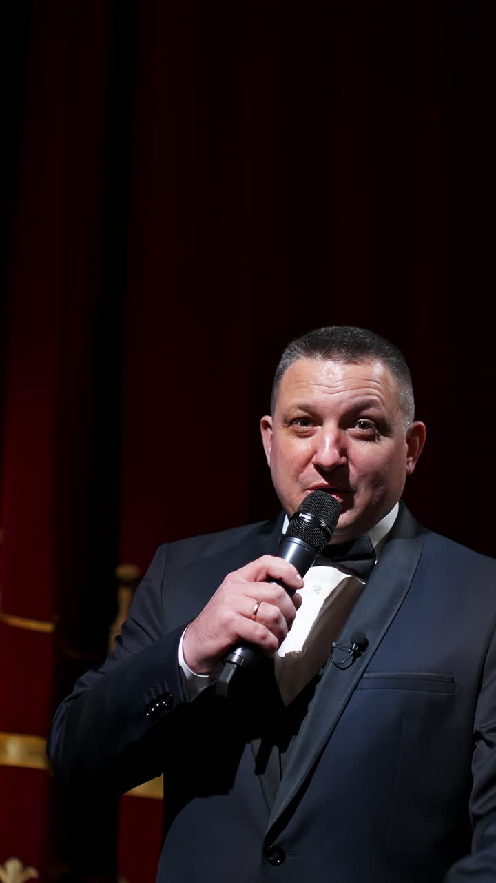 Actor with microphone announces performance before auditorium. Theater curtains background. Vertical video