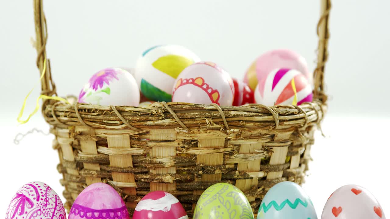 Cesto con uova di Pasqua dipinte su sfondo bianco