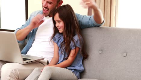 Happy-father-and-daughter-using-laptop