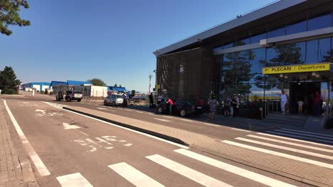 airport departures terminal entrance with people and cars