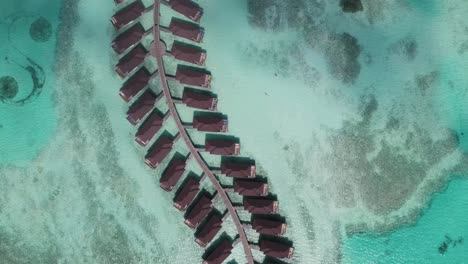 Overwater-bungalows-in-Maldives-surrounded-by-turquoise-sea,-aerial-view