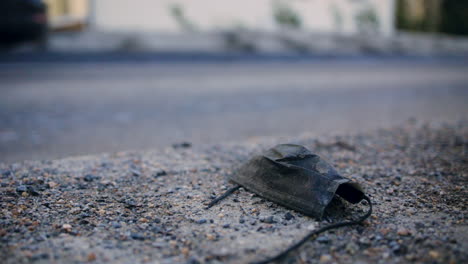 Close-up-slomo-of-black-face-mask-on-ground-as-car-passes-behind-it