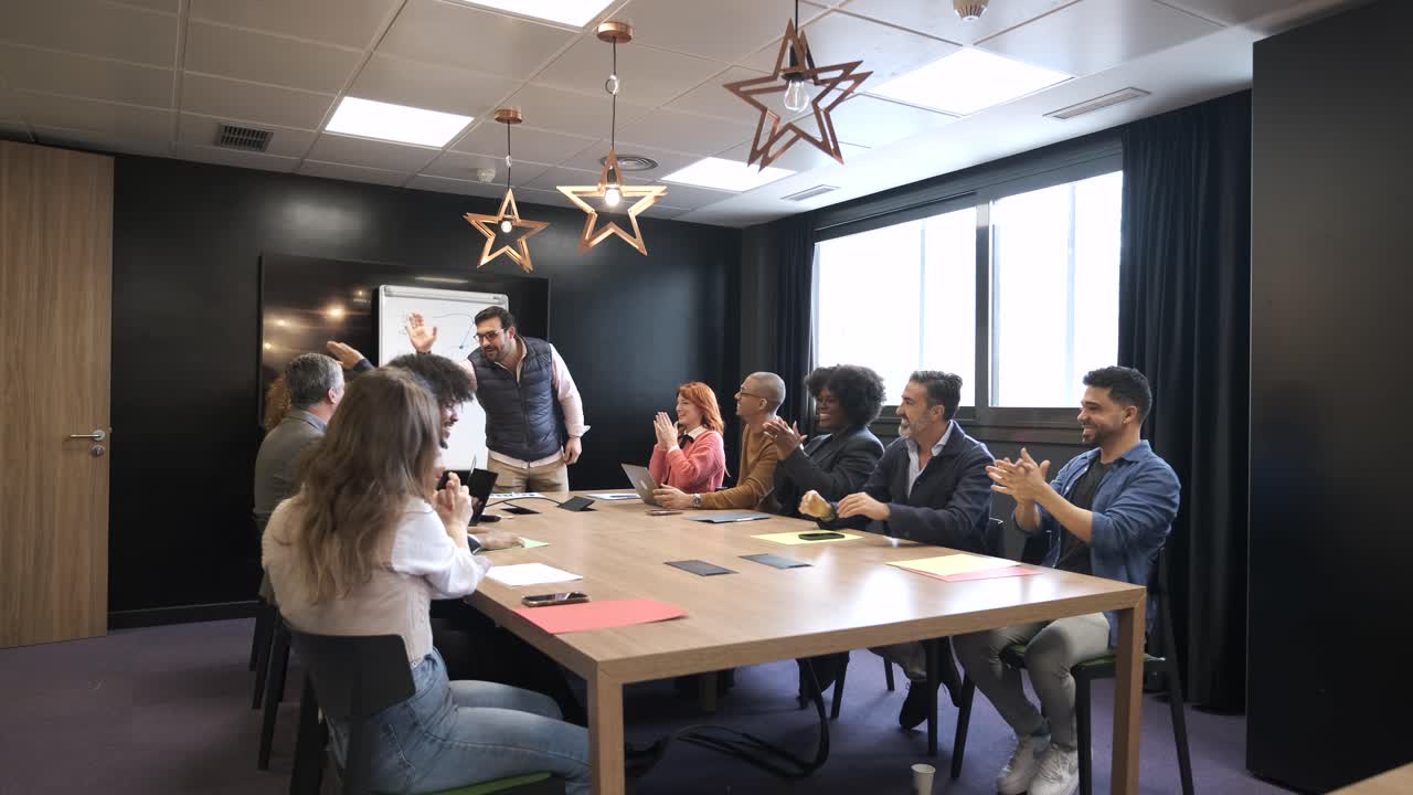 Businessman telling good news to diverse colleagues in conference room
