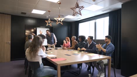 businessman telling good news to diverse colleagues in conference room