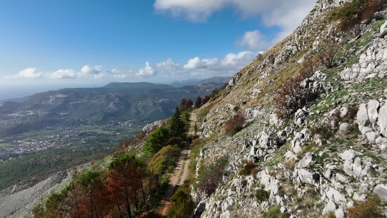 vista aérea de un paisaje montañoso con carretera de tierra y vehículo