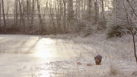 A-cyclist-rides-past-L2R-as-the-ice-bather-sits-in-freezing-cold-water,-golden-light