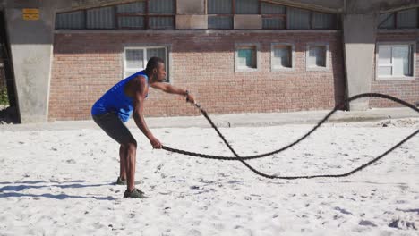 Fokussierter-Afroamerikanischer-Mann,-Der-Draußen-Am-Strand-Mit-Kampfseilen-Trainiert