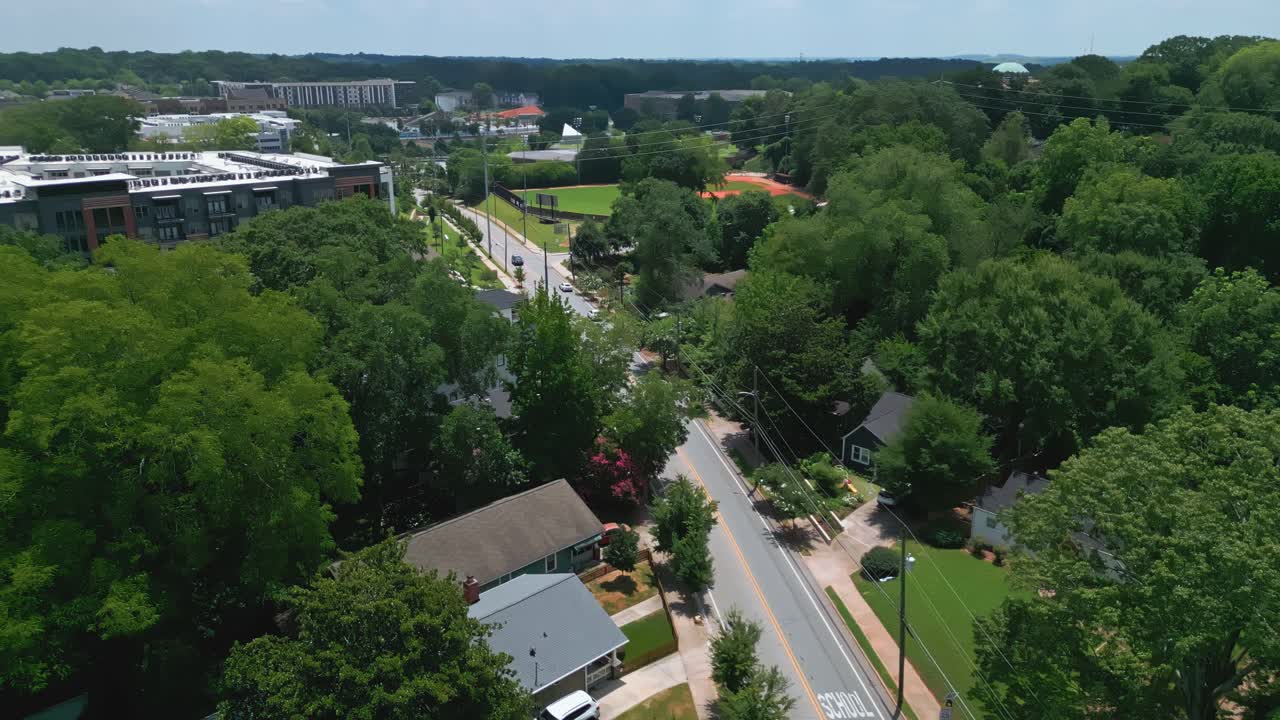 Cars on suburb street in idyllic quiet suburb neighborhood of Atlanta. Sunny day with green trees in town. Aerial wide shot. Houses and homes in suburbia