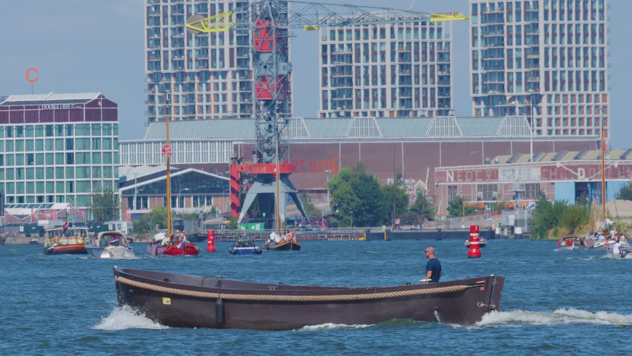 Single motorboat moves across Amsterdam river, daytime, modern buildings, wide shot, steady camera