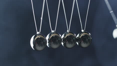 close-up of newton's cradle - metal balls hit one another and show energy conservation effect