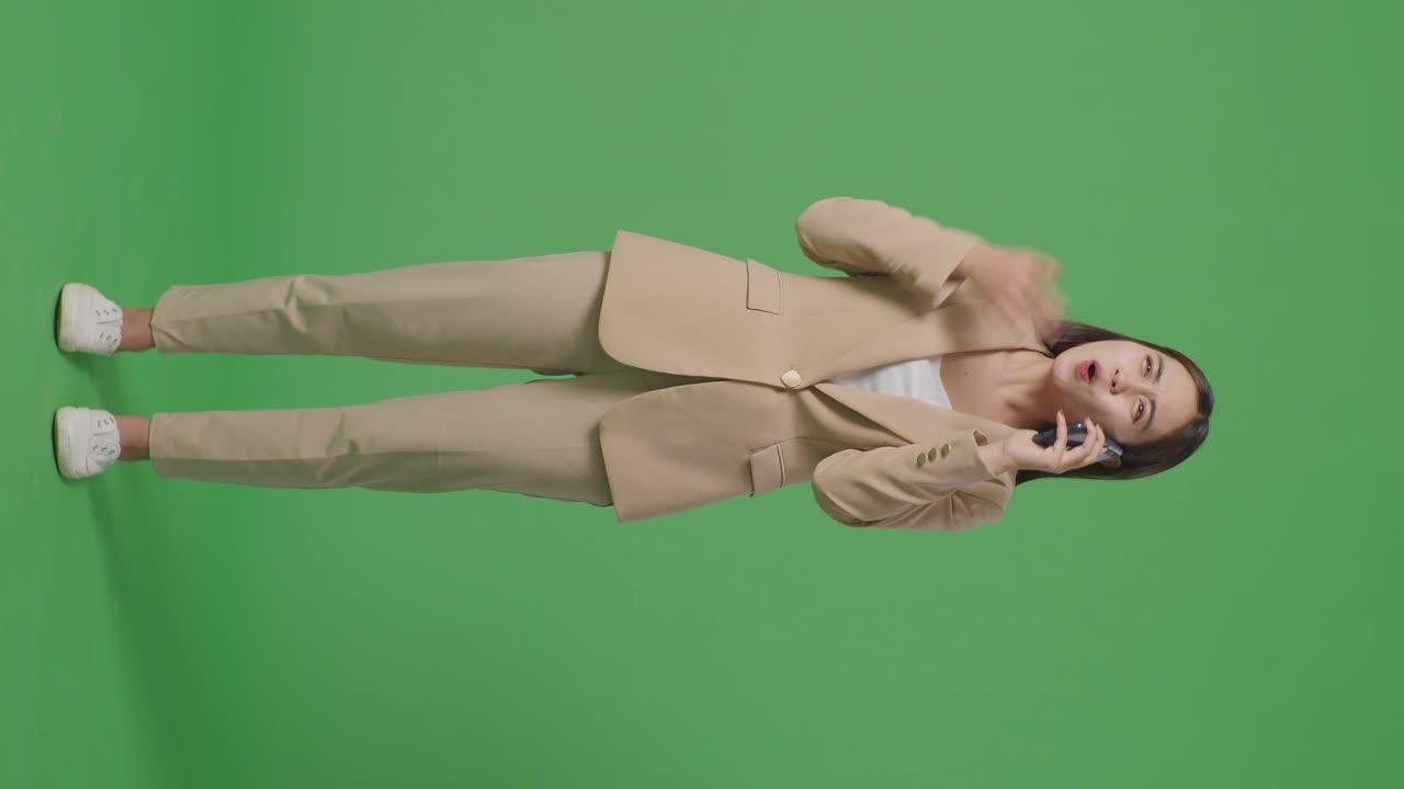스튜디오에서 녹색 화면에 서 있는 동안 휴대 전화로 이야기하는 분노 아시아 사업가의 몸이 가득 차 있습니다.