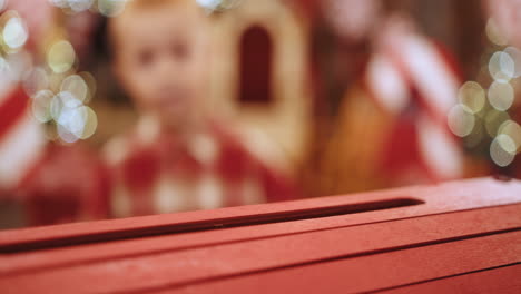 niño mirando una caja roja de navidad