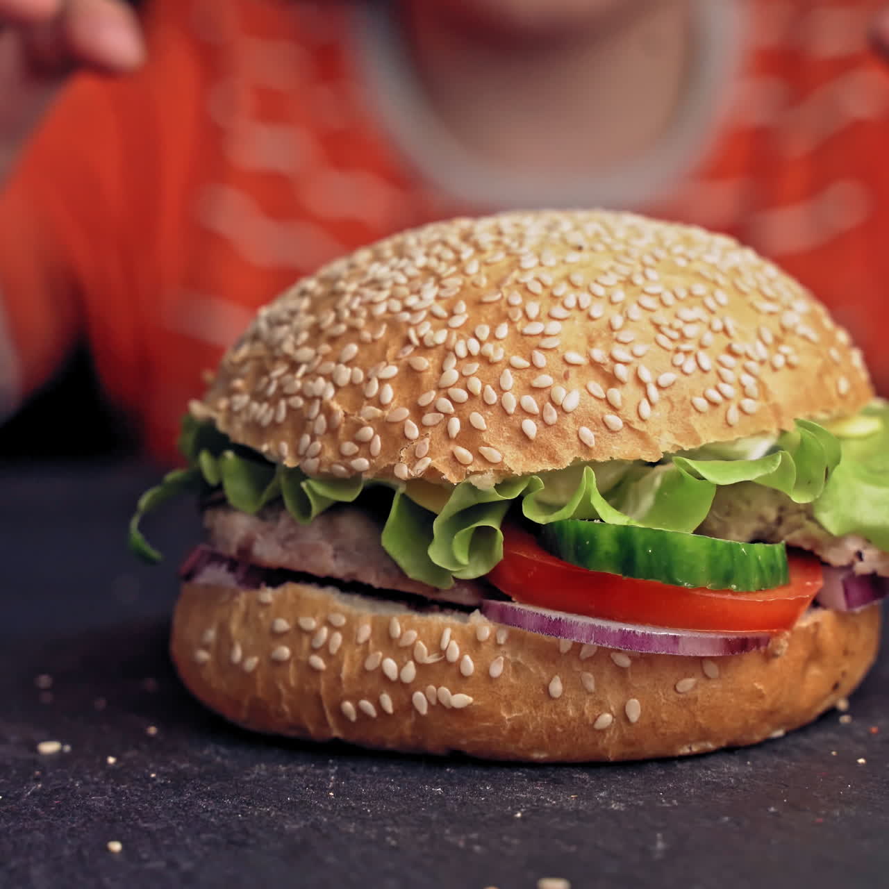 Young teenager eating tasty hamburger in fast food restaurant