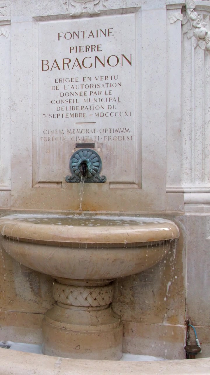 Inquadratura media statica di una fontana in pietra intagliata con acqua che scorre a Cassis, Francia.