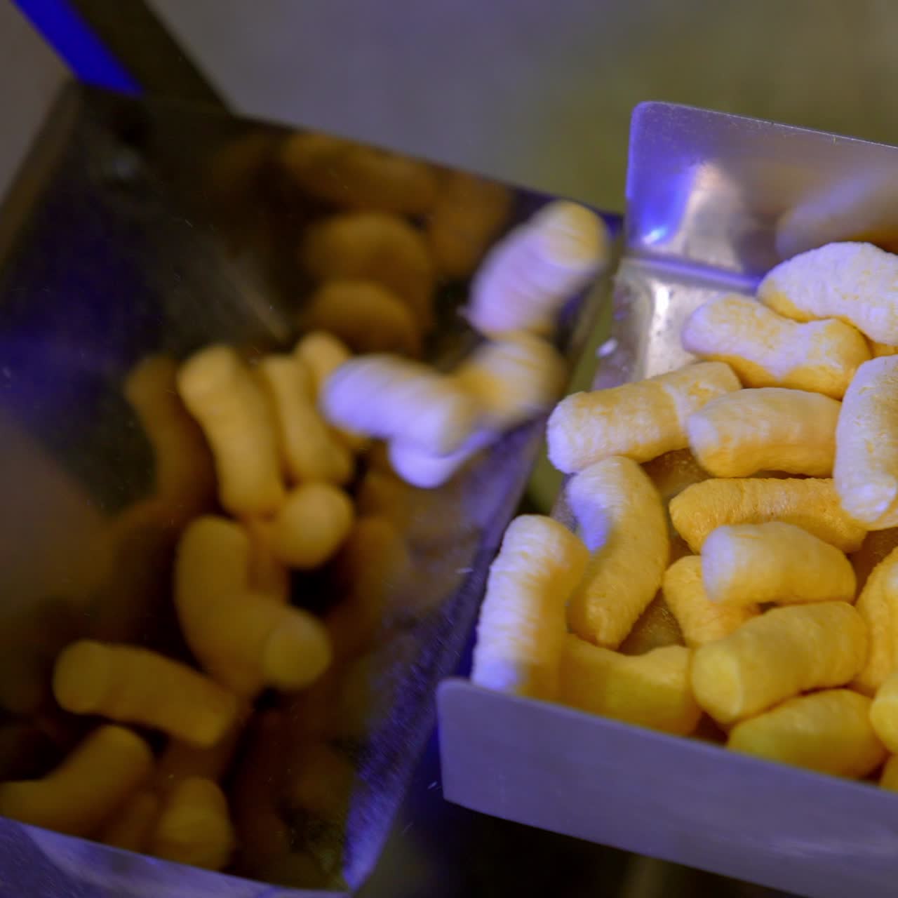 Light crispy corn sticks being pushed on the conveyor belt. Maize snacks production at factory. Vegetarian food concept