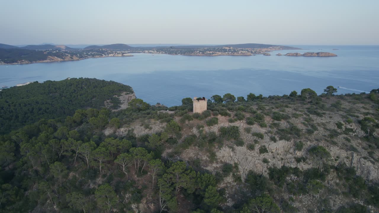Aerial View of a Historic Coastal Watchtower on a Forested Hill Overlooking a Mediterranean Bay