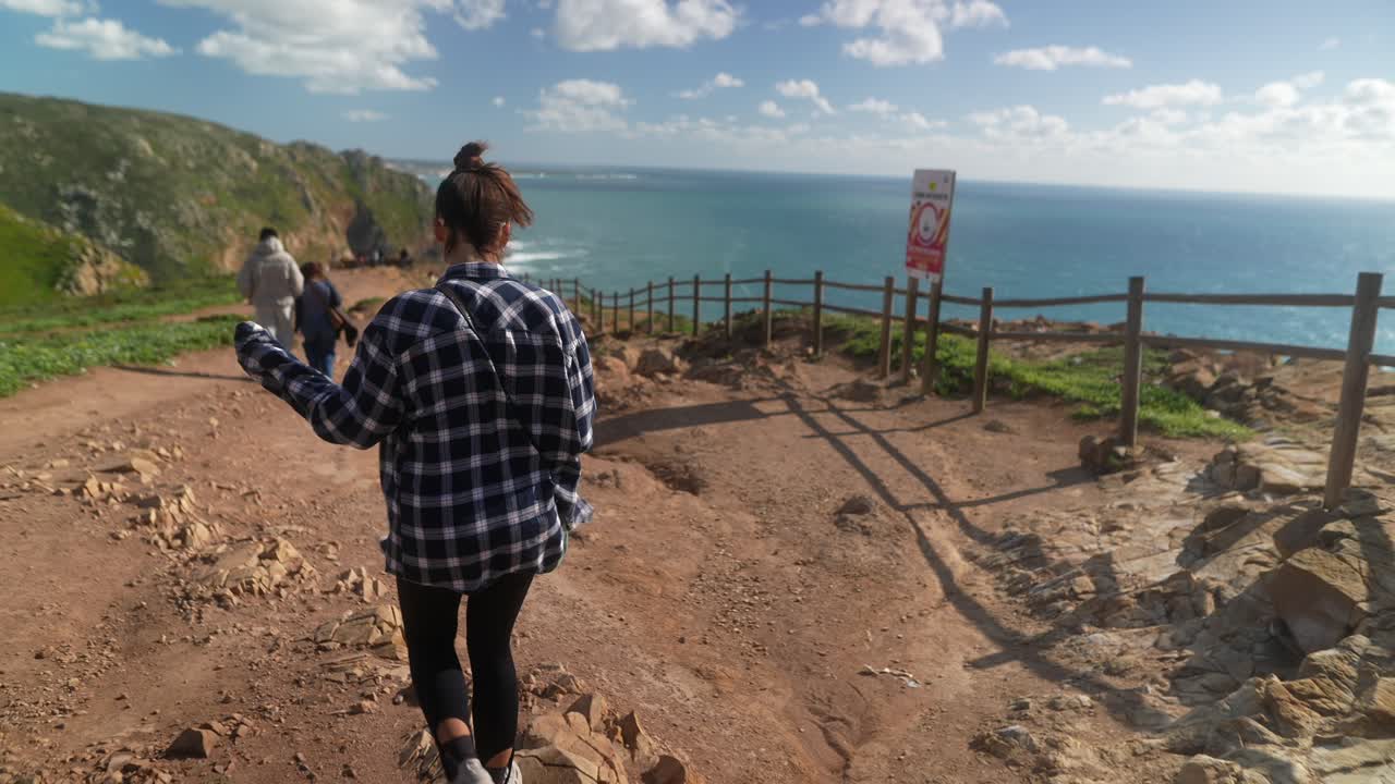 женщина, идущая по прибрежной тропе.