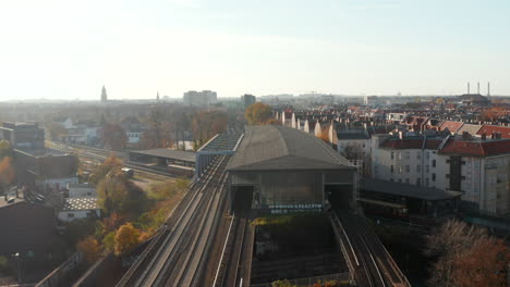 Empty-Train-Station-elevated-above-Street-in-German-Big-City-Berlin-at-beautiful-Autumn-Sunset,-Aerial-Dolly-in