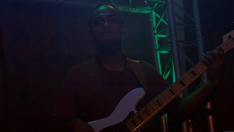 male musician playing white bass guitar on music concert stage creating green truss graphics