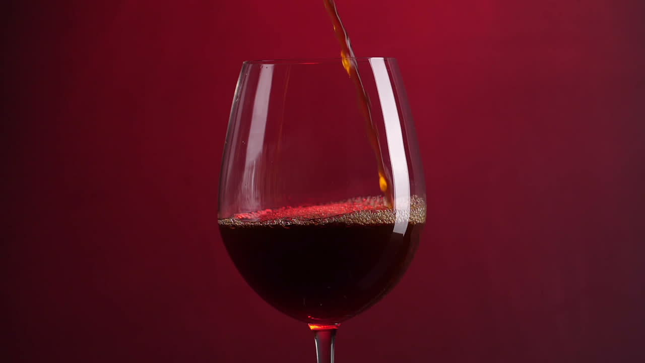 Pouring A Glass Of Wine With Red Background, Slow Motion