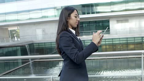 Serious-businesswoman-with-tablet-pc-on-street