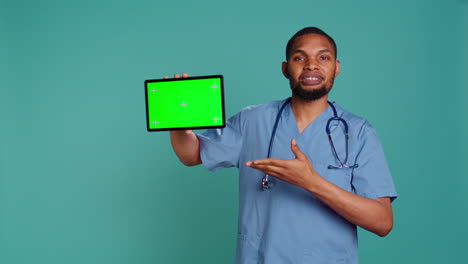 Cheerful-nurse-showing-medical-instructions-video-on-chroma-key-tablet