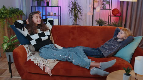 two teenage girls laughing and relaxing on a couch together